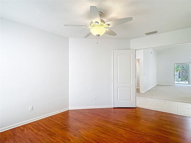 empty room featuring visible vents, baseboards, a ceiling fan, and wood finished floors