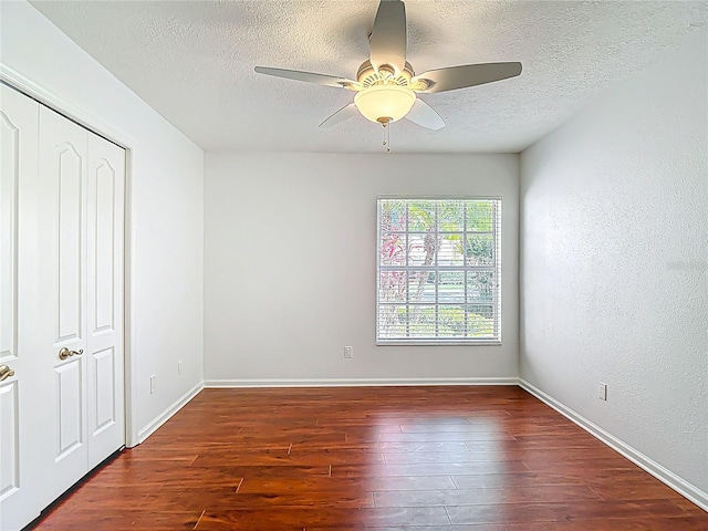 unfurnished bedroom featuring a textured ceiling, wood finished floors, and baseboards