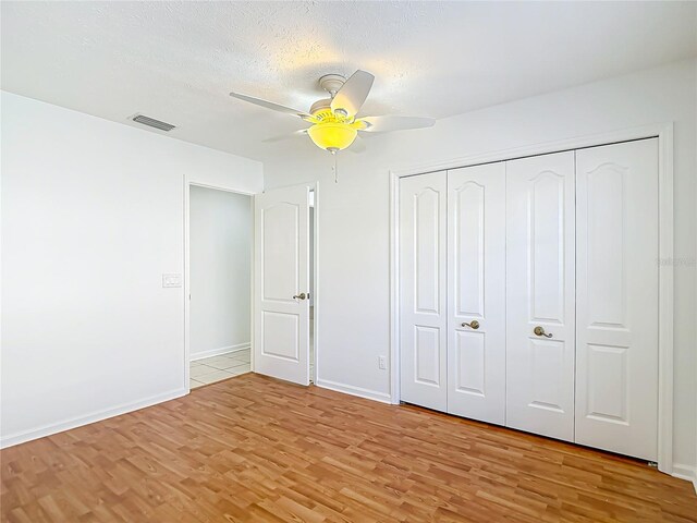 unfurnished bedroom featuring visible vents, baseboards, a closet, ceiling fan, and light wood-style flooring
