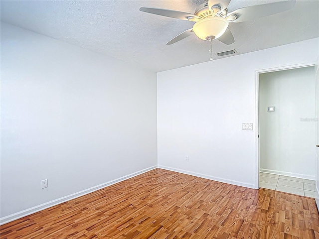 spare room featuring wood finished floors, baseboards, a ceiling fan, and visible vents