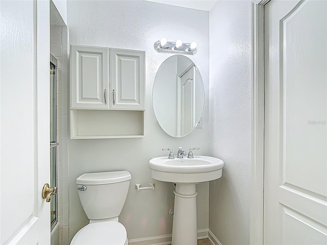 bathroom featuring baseboards, walk in shower, and toilet