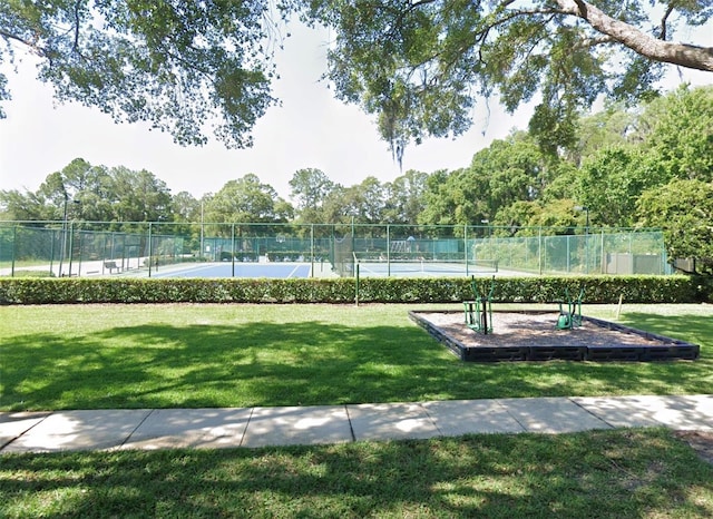 view of home's community featuring a lawn, a tennis court, and fence