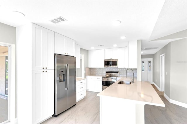 6994 Country Lakes Cir, Sarasota, FL 34243 - kitchen with stainless steel appliances, a peninsula, light countertops, white cabinetry, and decorative backsplash