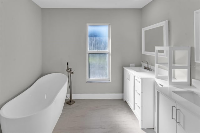 6994 Country Lakes Cir, Sarasota, FL 34243 - bathroom with two vanities, marble look tiles, a freestanding bath, and plenty of natural light