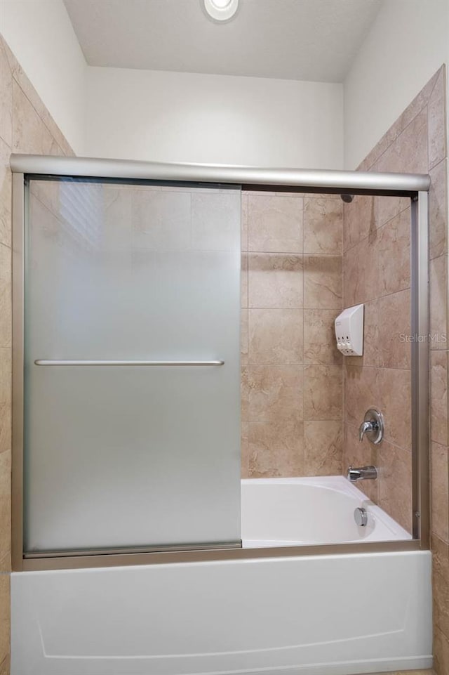 bathroom featuring bath / shower combo with glass door