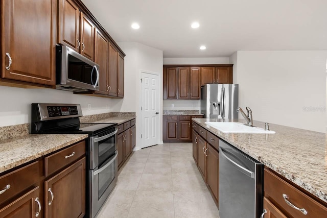 kitchen featuring light tile patterned floors, light stone countertops, recessed lighting, appliances with stainless steel finishes, and a sink