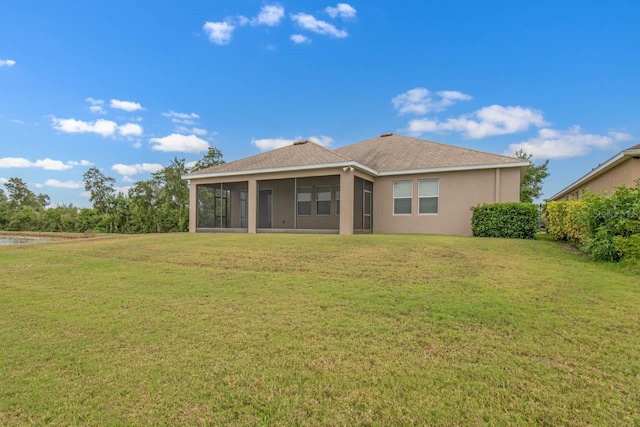 back of property featuring a sunroom, a yard, a shingled roof, and stucco siding