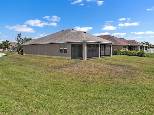 rear view of property featuring a yard, stucco siding, and a sunroom