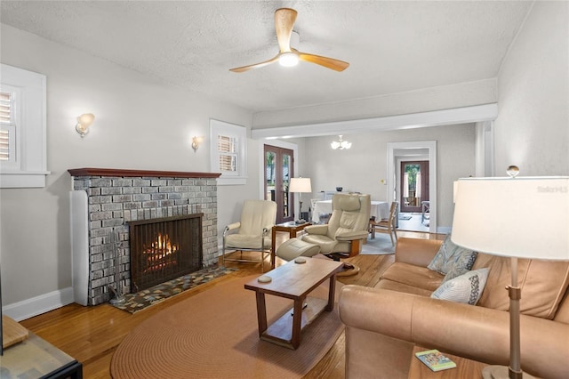 3120 8th Ave N, Saint Petersburg, FL 33713 - living room with wood finished floors, a brick fireplace, ceiling fan, a textured ceiling, and baseboards