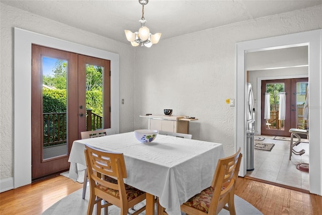 3120 8th Ave N, Saint Petersburg, FL 33713 - dining space with french doors, healthy amount of natural light, a textured wall, a chandelier, and light wood-style flooring