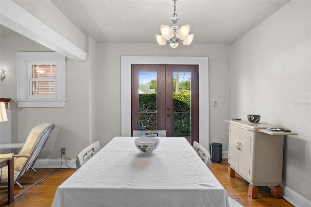 3120 8th Ave N, Saint Petersburg, FL 33713 - dining area with a chandelier, a textured wall, wood finished floors, french doors, and baseboards