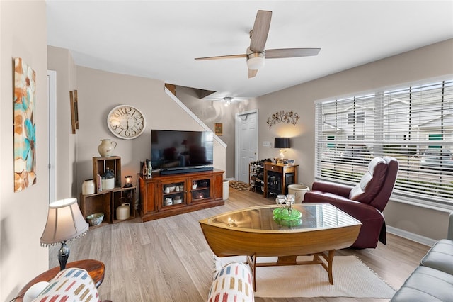 living area with light wood-type flooring, a ceiling fan, and baseboards