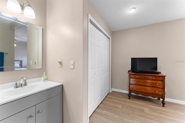 bathroom with wood finished floors, vanity, and baseboards