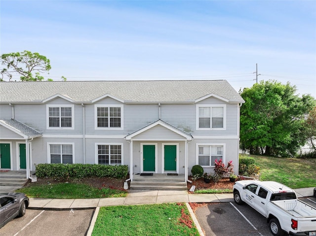 townhome / multi-family property featuring uncovered parking and a shingled roof