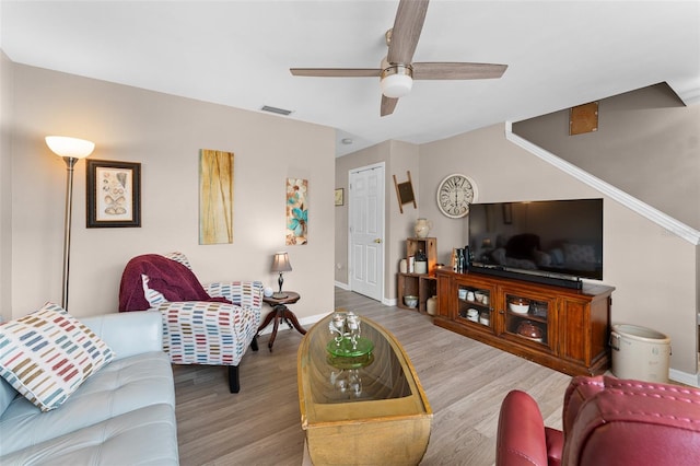living room featuring ceiling fan, baseboards, and wood finished floors