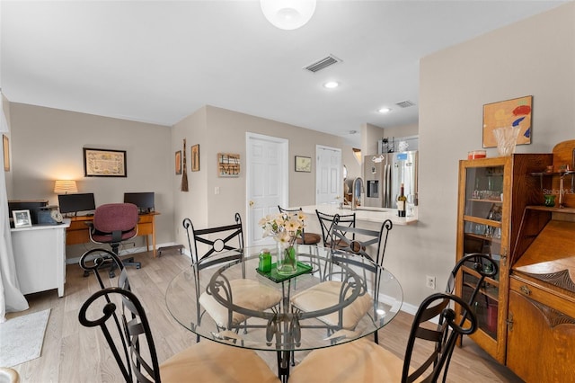 dining space featuring baseboards, light wood-type flooring, and a desk