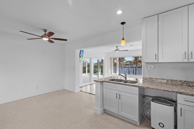 2540 S Shore Dr SE, Saint Petersburg, FL 33705 - kitchen with a sink, a water view, a ceiling fan, light stone counters, and white cabinetry