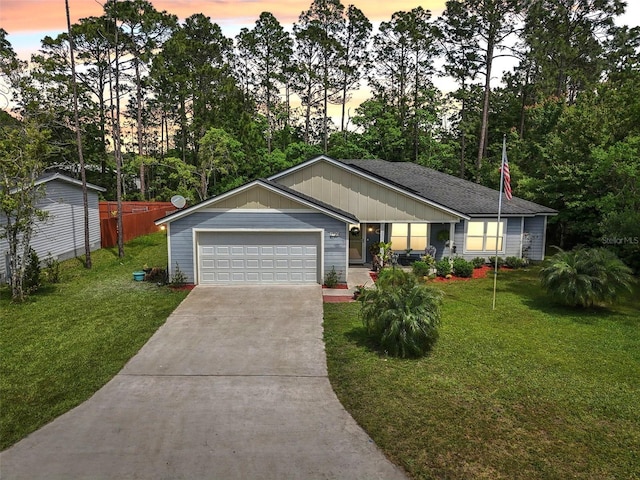 single story home featuring concrete driveway, an attached garage, and view of wooded area