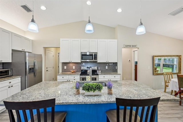 2720 N Screech Owl Ave, Saint Augustine, FL 32084 - kitchen featuring stainless steel appliances, vaulted ceiling, a kitchen breakfast bar, decorative backsplash, and pendant lighting