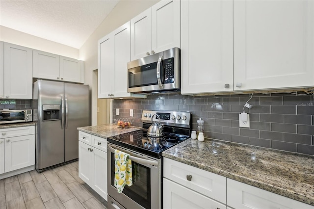 2720 N Screech Owl Ave, Saint Augustine, FL 32084 - kitchen featuring appliances with stainless steel finishes, decorative backsplash, stone countertops, white cabinets, and a textured ceiling