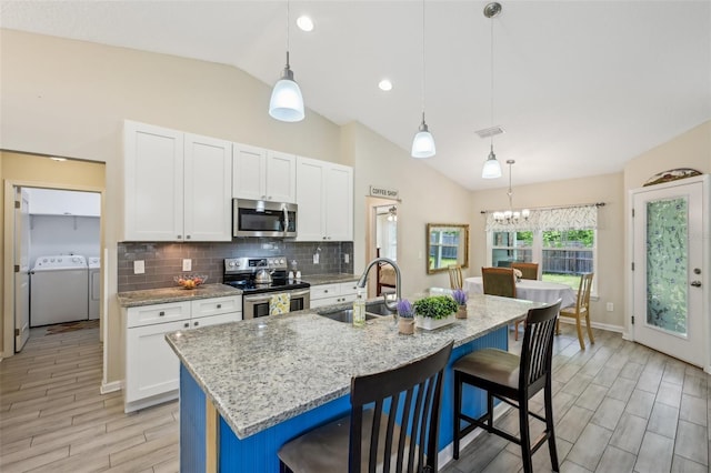 2720 N Screech Owl Ave, Saint Augustine, FL 32084 - kitchen featuring stainless steel appliances, washing machine and clothes dryer, a sink, lofted ceiling, and white cabinetry