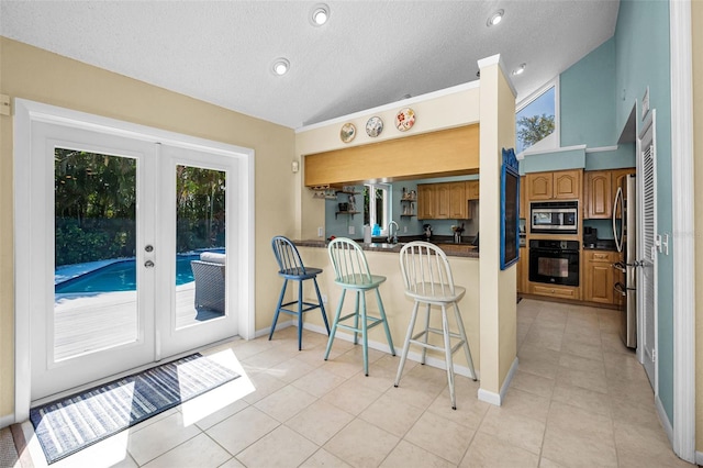508 N Mayo St, Crystal Beach, FL 34681 - kitchen with brown cabinetry, french doors, a kitchen bar, stainless steel microwave, and oven