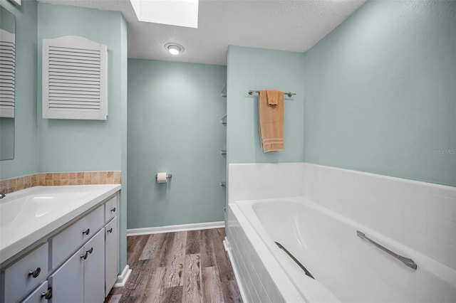 508 N Mayo St, Crystal Beach, FL 34681 - bathroom with vanity, wood finished floors, a textured ceiling, a bath, and a skylight