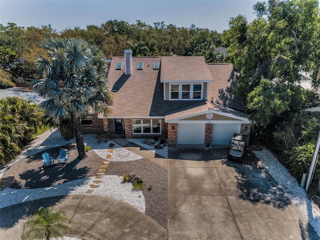 508 N Mayo St, Crystal Beach, FL 34681 - view of front of house featuring driveway, a chimney, a shingled roof, and stone siding