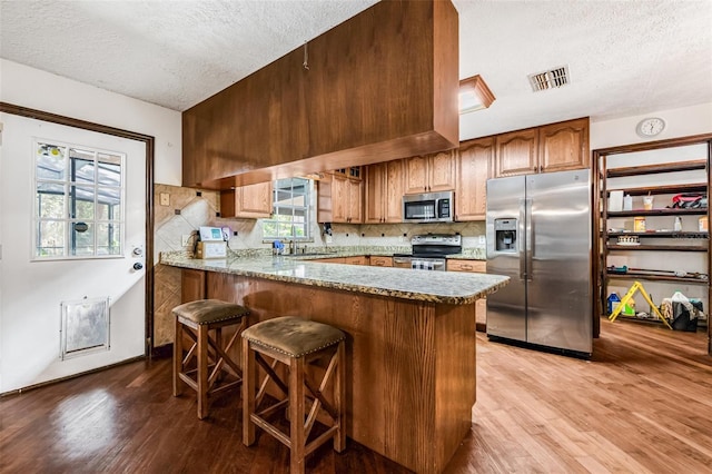 kitchen with light wood finished floors, visible vents, appliances with stainless steel finishes, and a textured ceiling