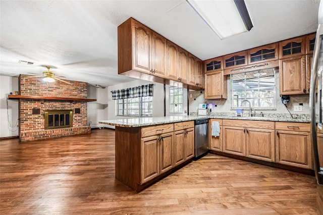 kitchen featuring light wood-style flooring, a sink, ceiling fan, a peninsula, and stainless steel dishwasher