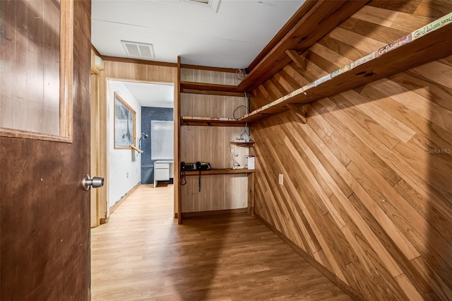 interior space with wooden walls, visible vents, and light wood-style floors
