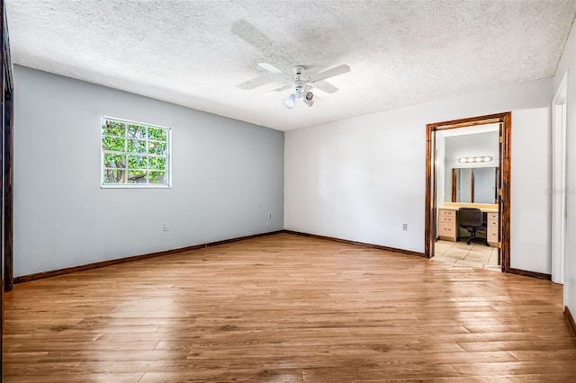 unfurnished bedroom featuring ensuite bathroom, baseboards, a ceiling fan, a textured ceiling, and light wood-style flooring