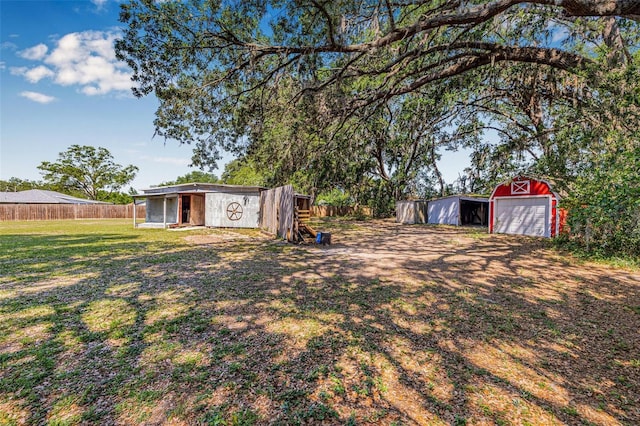 view of yard with an outbuilding, an outdoor structure, fence, and a detached garage