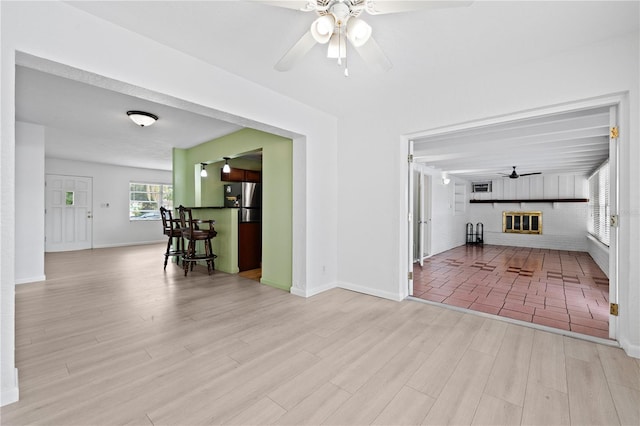 living room with baseboards, a fireplace, a ceiling fan, and wood finished floors
