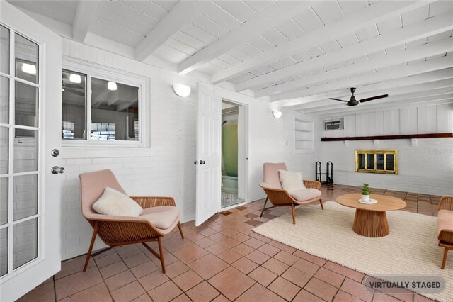 living area featuring tile patterned floors, a ceiling fan, beam ceiling, and a brick fireplace