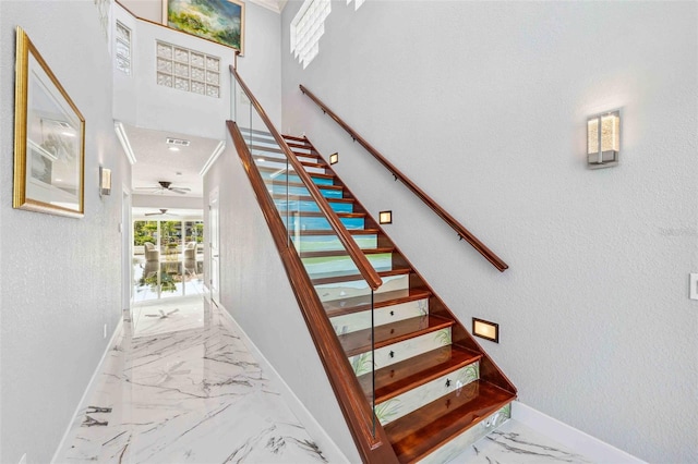 stairway featuring visible vents, marble finish floor, a textured wall, baseboards, and a ceiling fan