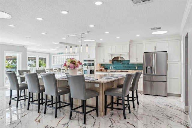 kitchen with backsplash, a textured ceiling, a spacious island, stainless steel appliances, and white cabinetry