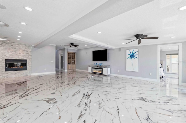 unfurnished living room featuring ceiling fan, a textured ceiling, beam ceiling, baseboards, and a glass covered fireplace