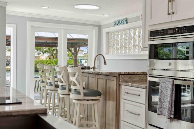 bar featuring crown molding and stainless steel double oven