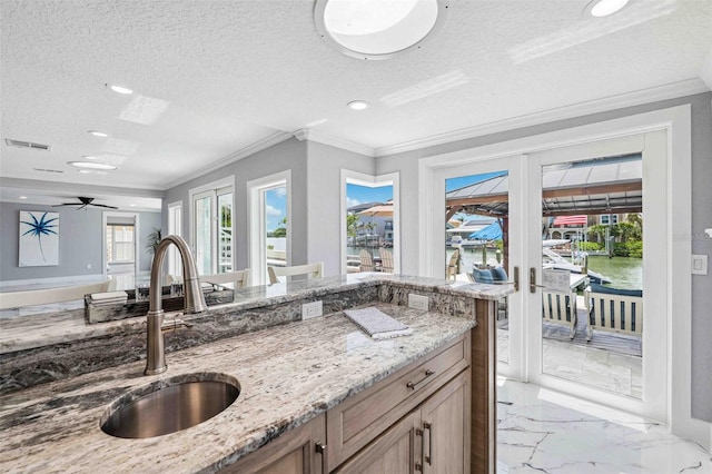 kitchen with light stone countertops, a sink, french doors, marble finish floor, and visible vents
