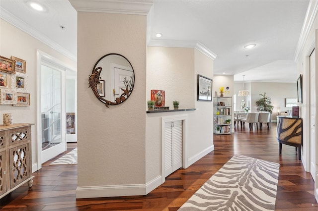 hallway with dark wood finished floors, ornamental molding, and a textured wall
