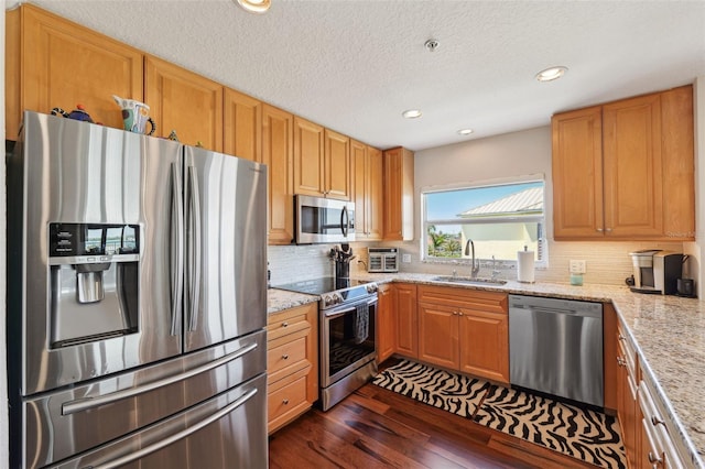 kitchen featuring appliances with stainless steel finishes, dark wood-style flooring, decorative backsplash, and a sink