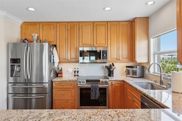 kitchen with light stone counters, stainless steel appliances, backsplash, and a sink