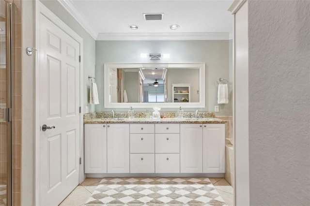 bathroom featuring a sink, crown molding, a tile shower, double vanity, and visible vents