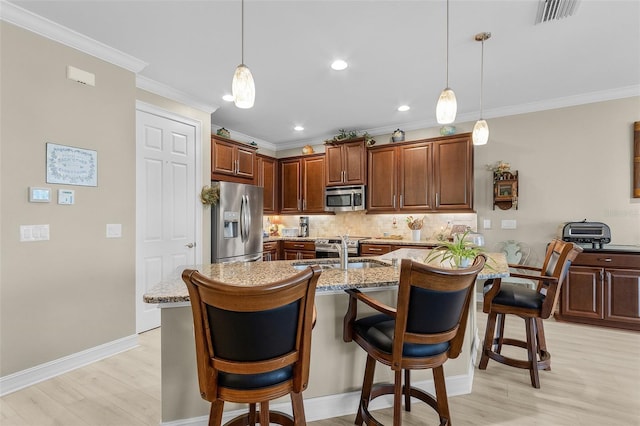 20605 Long Pond Rd, North Fort Myers, FL 33917 - kitchen with appliances with stainless steel finishes, a sink, light wood-style flooring, a kitchen breakfast bar, and backsplash