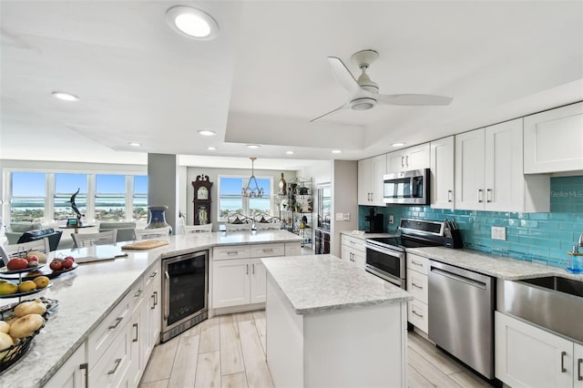 5200 Brittany Dr S Unit 1502, Saint Petersburg, FL 33715 - kitchen featuring backsplash, a kitchen island, white cabinets, wine cooler, and appliances with stainless steel finishes