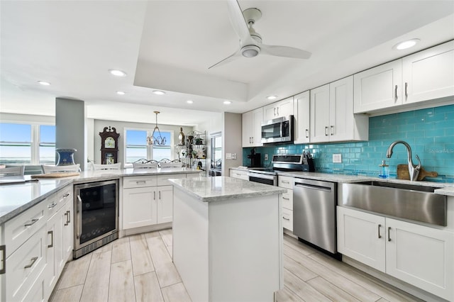5200 Brittany Dr S Unit 1502, Saint Petersburg, FL 33715 - kitchen featuring appliances with stainless steel finishes, a sink, a center island, wine cooler, and decorative backsplash