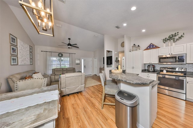 8805 Van Fleet Rd, Riverview, FL 33578 - kitchen with open floor plan, appliances with stainless steel finishes, white cabinetry, vaulted ceiling, and ceiling fan with notable chandelier