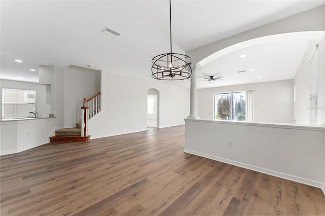unfurnished living room featuring arched walkways, wood finished floors, and a wealth of natural light