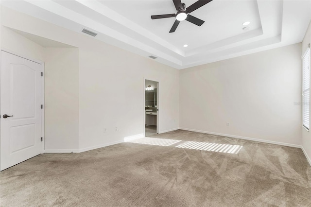 unfurnished room featuring a raised ceiling, visible vents, ceiling fan, and carpet